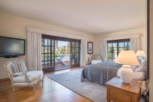 a bedroom with a bed and a tv and a chair at Villa Sildavia in Estepona +42 photos