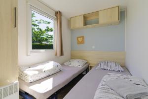 two beds in a room with a window at Mobilhome 373 in Lattes +17 photos