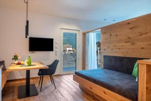 a bedroom with a bed and a desk and a television at Luisl Hof - Apartment Pomum in Cornaiano
