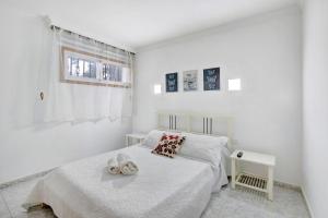 a white bedroom with a bed and a window at Apartamento Mertxe in Arona
