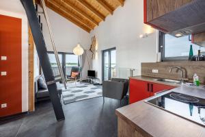 a kitchen with red cabinets and a living room at Ferienhaus Sonnenwind Hainer See Og in Neukieritzsch