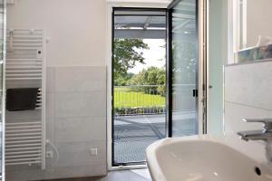 a bathroom with a sink and a sliding glass door at Ferienwohnung Donautal in Meßkirch +17 photos
