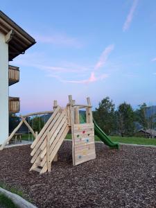 a wooden playground with a slide in a yard at Forchnerhof Apt Ploseblick in Maranza
