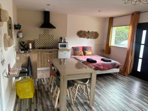 a room with a table and a bed and a kitchen at L'Ambréenne in Sainte-Cécile
