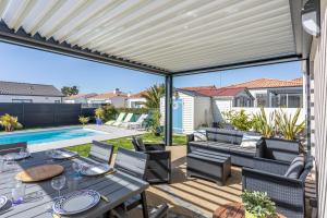 a patio with a table and chairs and a pool at Maison Salorge - piscine privée in Jard-sur-Mer