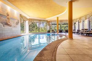 a swimming pool in a building with windows and a pool at Sabina Dolomites Birke in Alpe di Siusi