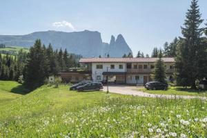 a building with cars parked in a field of flowers at Sabina Dolomites Birke in Alpe di Siusi