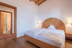 a bedroom with a large bed with a wooden headboard at Sabina Dolomites Birke in Alpe di Siusi +26 photos