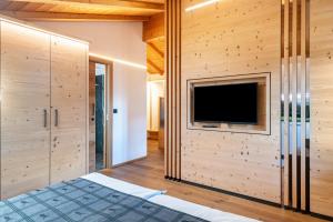 a bedroom with wooden walls and a flat screen tv at Schreiberhof Charme in Laion