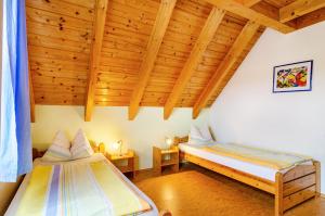 two beds in a room with a wooden ceiling at Beutenmühle Straussenfarm Dach in Owingen