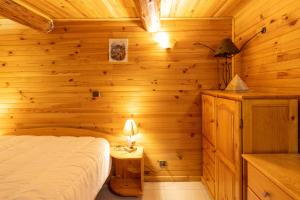 a log cabin bedroom with a bed and a lamp at Chalet D'alpage Authentique in Queige