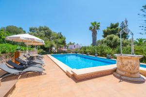 a swimming pool with chairs and an umbrella at Villa Juana Maria in Cala Murada
