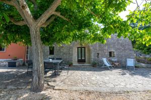 a patio with a table and chairs under a tree at I Trulli di Dona Filomena in Selva di Fasano