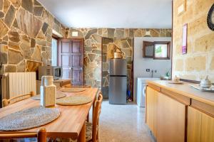 a kitchen with a wooden table and a stone wall at I Trulli di Dona Filomena in Selva di Fasano