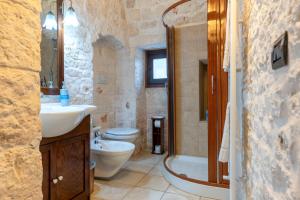 a bathroom with a sink and a toilet and a shower at I Trulli di Dona Filomena in Selva di Fasano