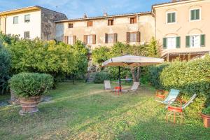 a garden with an umbrella and chairs and a building at Villa Gabriella - Piazzano in Lucca