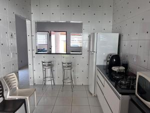 a kitchen with a refrigerator and stools in it at Casa jardim fonte nova in Goiânia