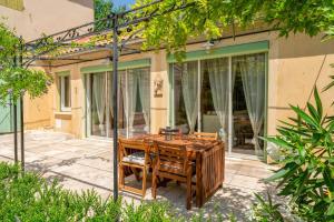 a wooden table and chairs in front of a house at Le Secret D'hestia in Bollène