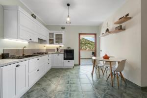a kitchen with white cabinets and a table with chairs at Buggerru Hugo House in Buggerru