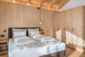 two beds in a room with wooden walls at Les Ciases Chalets Dolomites Apt 6 in San Vigilio Di Marebbe