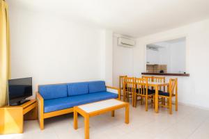 a living room with a blue couch and a table at Apartament Massanet ba in Canyamel