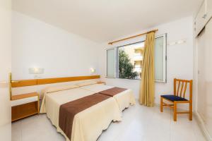 a bedroom with a bed and a chair and a window at Apartament Massanet ba in Canyamel