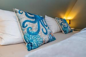 a bed with white pillows and a blue and white pillow at Gemütliche Wohnung Reet-Pool-Sauna in Keitum +25 photos
