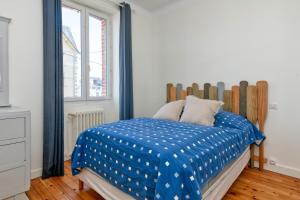 a bedroom with a bed with a blue comforter at La Maison de Port Lin in Le Croisic