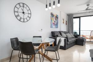 a living room with a couch and a table and a clock at Roya Vistamar in Torrox Costa