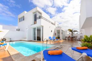 a villa with a swimming pool and blue chairs at Luis iii in Puerto del Carmen