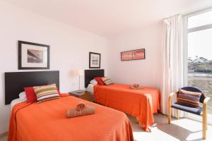 a bedroom with two beds with orange sheets and a window at Luis iii in Puerto del Carmen +23 photos