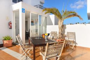 a table and chairs on a patio with a palm tree at Luis iii in Puerto del Carmen