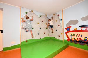 two children climbing a rock wall in a play room at Alpenchalet Niederkofler Isabella in San Giovanni in Val Aurina