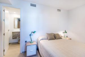a white bedroom with a bed and a lamp on a night stand at Beach Pearl Cala de Mijas in Mijas