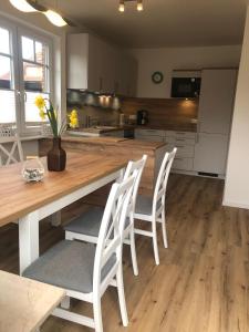 a kitchen with a wooden table and white chairs at Fjordstrand in Borgwedel