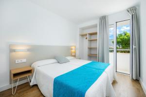 a white bedroom with a bed and a window at Apartament Massanet 1b in Canyamel