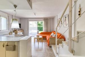 a living room with an orange couch and a kitchen at Pinamar casa con piscina in L'Escala