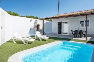 a backyard with a swimming pool and chairs and a house at La Teja 3 - Solo Familias in Vejer de la Frontera