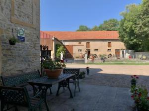 a patio with a table and chairs and a building at Gite L'atelier De Théophile in Peltre