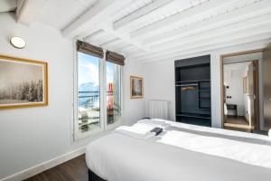 a white bedroom with a large bed and two windows at Triplex By Popalp in LʼHuez