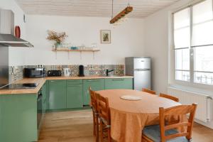 a kitchen with green cabinets and a table with chairs at La Pointe Du Crotoy in Le Crotoy