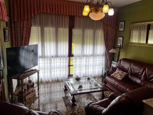 a living room with a leather couch and a television at Villa Neli Playa in Foz