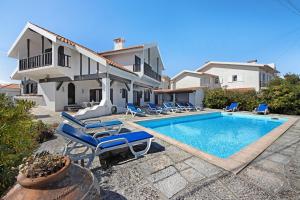 a villa with a swimming pool and blue lounge chairs at Casa Do Bico Da Biarritz in Costa Nova