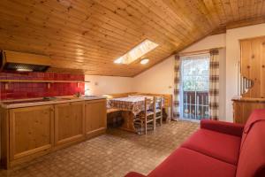 a kitchen with a table and a red couch in a room at Casa Lorenz 4 in Canazei