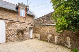 an old brick building with a white door and a tree at Appart Cancale Centre-ville - Mer in Cancale