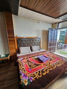a bedroom with a large bed with a blanket on it at Smarthill Deodar Echoes in Dalhousie