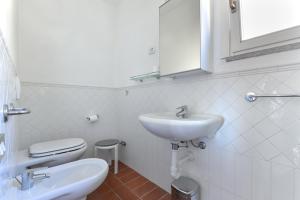a white bathroom with a sink and a toilet at Casa Ebaté in Chiessi +18 photos
