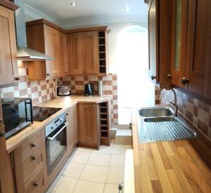 una cocina con armarios de madera y fregadero en Castle Cottage en Rayleigh