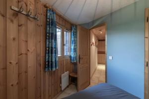 a bedroom with wood paneling and a blue curtain at L’Edelweiss Pied des Pistes in Morillon
