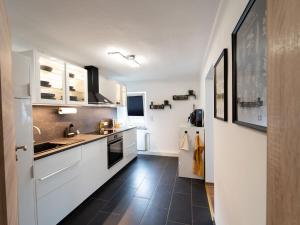 a kitchen with white cabinets and a black tile floor at Ferienwohnung Sunny in Schmallenberg
